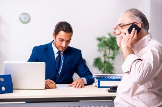 Foto: Pensionist telefoniert, Sachbearbeiter am Schreibtisch