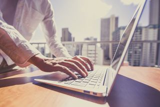 Foto: Laptop mit Hochhäusern im Hintergrund